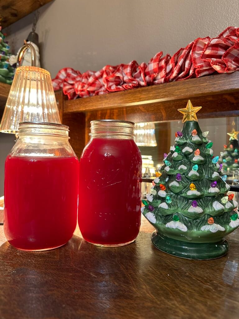 Two jars of cranberry juice next to a vintage ceramic Christmas tree.